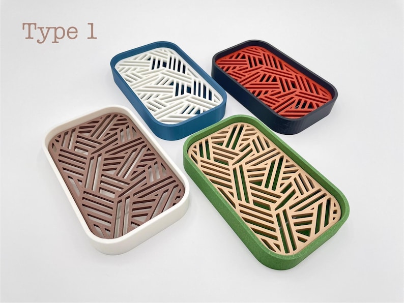 May include: Four rectangular trays with geometric cut-out designs. The trays are in various colors: white and blue, red and black, brown and white, and green and tan. The text "Type 1" is in the upper left corner.