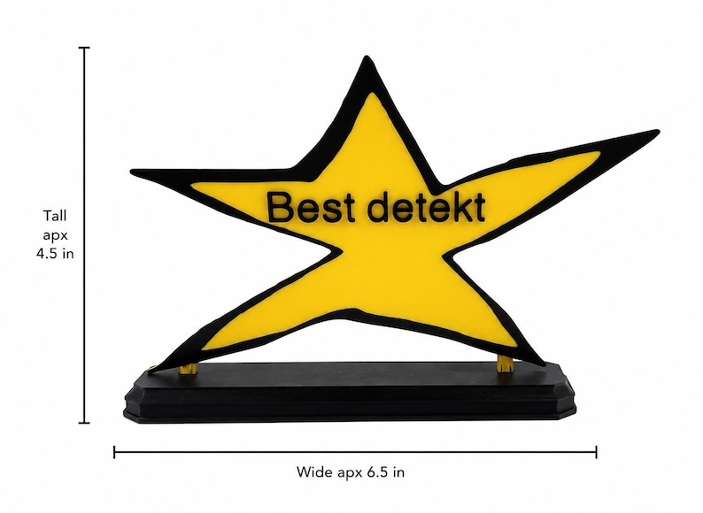 May include: A yellow star-shaped plaque with a black outline and the text "Best detekt" in black lettering. The star is mounted on a rectangular black base. The object measures approximately 4.5 inches tall and 6.5 inches wide.