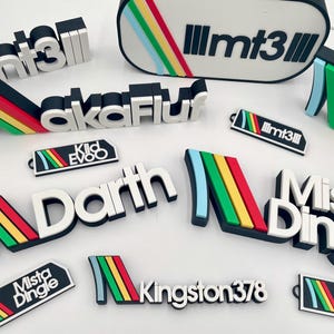 Może przedstawiać: Kolekcja różnych czarno-białych wzorów tekstu 3D z kolorowymi akcentami. Teksty obejmują "mt3", "akaFluf", "Kid Evoo", "Darth", "Mista Dingle" i "Kingston378". Każdy projekt zawiera tęczowy pasek.