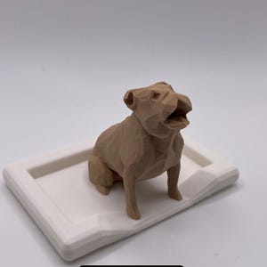 Puede incluir: Una figura geom&eacute;trica de bulldog ingl&eacute;s de color marr&oacute;n claro se encuentra sobre una bandeja rectangular blanca. El perro est&aacute; representado con la boca abierta. El texto "English Bulldog" se muestra en un rect&aacute;ngulo negro en la parte inferior de la imagen.