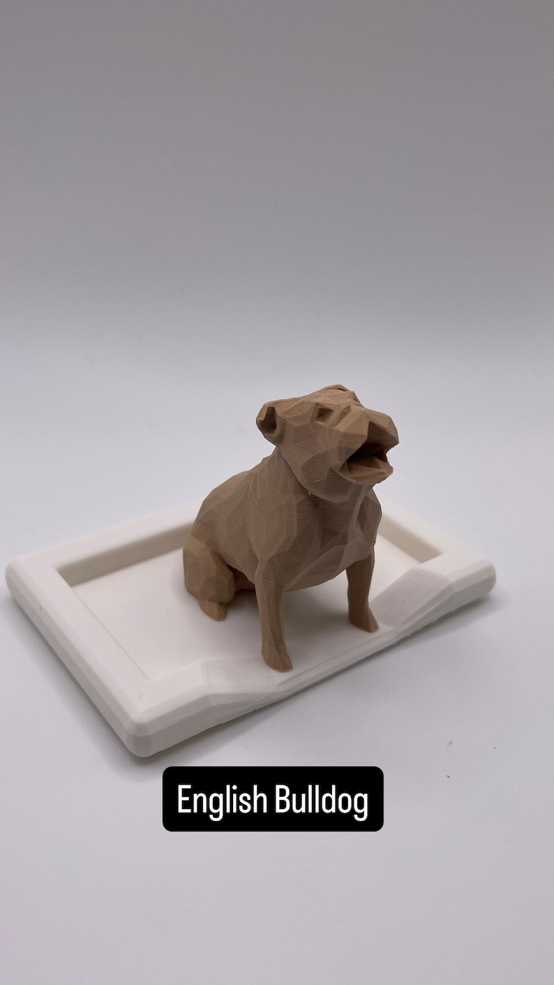 Puede incluir: Una figura geom&eacute;trica de bulldog ingl&eacute;s de color marr&oacute;n claro se encuentra sobre una bandeja rectangular blanca. El perro est&aacute; representado con la boca abierta. El texto "English Bulldog" se muestra en un rect&aacute;ngulo negro en la parte inferior de la imagen.