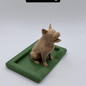 Puede incluir: Figura geom&eacute;trica de un bulldog franc&eacute;s marr&oacute;n claro, sobre una base rectangular verde texturizada. El texto "French Bulldog" se muestra en un rect&aacute;ngulo negro encima del perro. Es un art&iacute;culo decorativo.