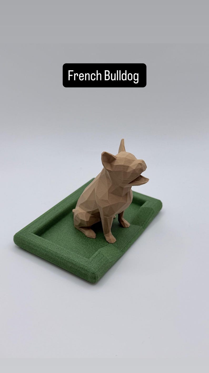 Puede incluir: Figura geom&eacute;trica de un bulldog franc&eacute;s marr&oacute;n claro, sobre una base rectangular verde texturizada. El texto "French Bulldog" se muestra en un rect&aacute;ngulo negro encima del perro. Es un art&iacute;culo decorativo.