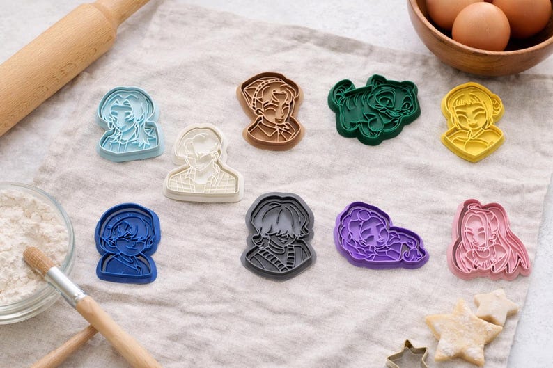 May include: A collection of nine plastic cookie cutters in various colors including light blue, white, brown, dark green, yellow, dark blue, gray, purple, and pink. Each cutter features a detailed embossed design of a different character portrait.