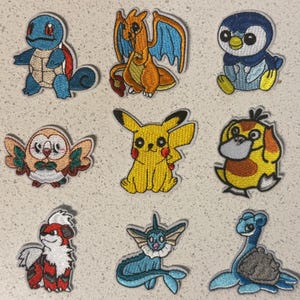 May include: Nine embroidered patches featuring cartoon characters. The patches include a blue turtle, an orange dragon, a blue penguin, a brown owl, a yellow mouse, a yellow and orange duck, a red and white dog, a blue mermaid-like creature, and a blue turtle-like creature.