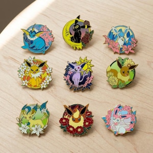 May include: A collection of nine enamel pins, each depicting a cartoon character within a floral border. The pins feature vibrant colours such as blue, yellow, purple, and green, with detailed designs and a shiny finish. Each pin presents a distinct design.