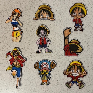 May include: A collection of embroidered patches featuring characters from the anime series One Piece. The patches showcase characters in various poses, with vibrant colors and detailed stitching. The characters include Luffy, Nami, and Chopper.