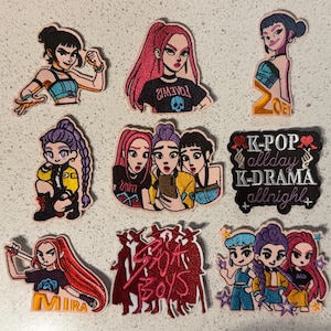 Op de afbeelding: Een verzameling geborduurde patches met gestileerde illustraties van vrouwelijke figuren en tekst. De patches tonen verschillende ontwerpen, waaronder portretten, tekst met de tekst "K-POP allday K-DRAMA allnight" en de tekst "BOYS".