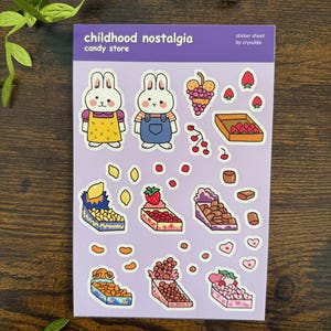 May include: A sticker sheet with a purple border featuring the text "childhood nostalgia candy store." The sheet includes bunny characters and illustrations of various candies and fruits, such as grapes, strawberries, and chocolates.