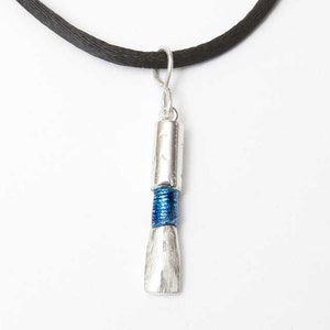 May include: A silver paintbrush pendant necklace with a blue and silver band on a black cord.