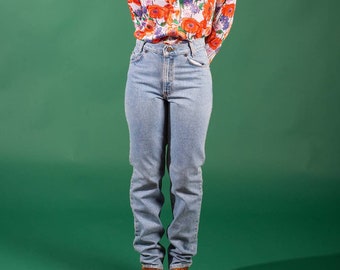 Könnte beinhalten: Eine Person trägt ein weißes Hemd mit Knöpfen und einem Blumendruck sowie eine blaue Jeans. Das Hemd hat orange, rote und lila Blumen.