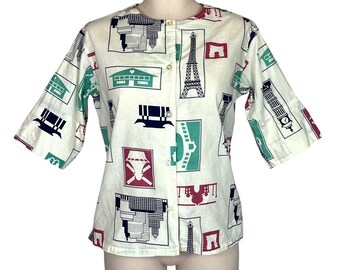 May include: A white button-up shirt with a short sleeve and a pattern of various landmarks in red, blue, green, and black. The shirt has a button-up front.