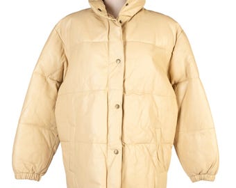 Pode incluir: Casaco puffer acolchoado creme com gola alta e fechos de pressão. O casaco tem uma silhueta quadrada e mangas compridas com punhos elásticos. O casaco é exibido em um manequim.