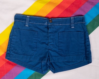 May include: A pair of blue denim shorts with white stitching and two large pockets on the front. The shorts have a button and zipper closure.