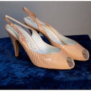 May include: A pair of light beige peep-toe slingback heels with a snakeskin pattern. The heels are made by Bruno Magli, Milan.