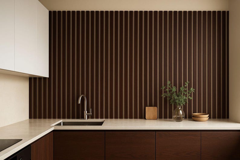 May include: Modern kitchen design featuring dark brown wood cabinetry and a matching vertical slat wall. A stainless steel faucet and sink are set into a light-colored countertop. Decorative elements include a small wooden cutting board, a glass vase with greenery, and two wooden bowls.