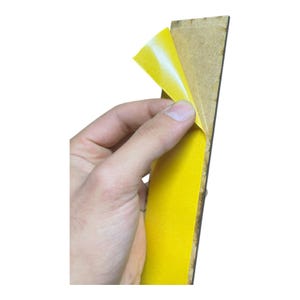 Pu&ograve; includere: Una mano che stacca del nastro adesivo giallo da una tavola di legno rettangolare. Il nastro &egrave; giallo brillante con un retro bianco, in contrasto con il legno marrone. L'immagine &egrave; su sfondo bianco.