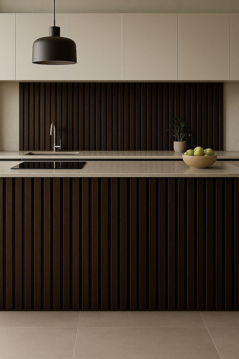 May include: Modern kitchen design featuring dark brown vertical wood paneling on the cabinets and backsplash. A light-colored countertop contrasts with the dark wood. A black pendant light hangs above the island. A bowl of green apples sits on the counter.