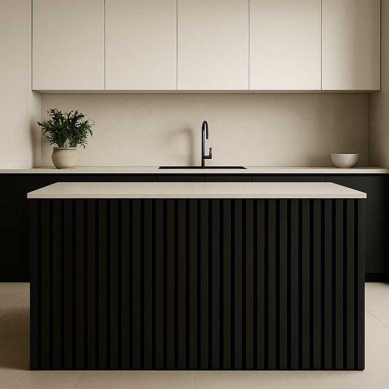 May include: Modern kitchen design featuring a black island with vertical slat detailing. The island has a light-colored countertop. Overhead, there are white cabinets and a black faucet. A potted plant and a white bowl add decorative elements.