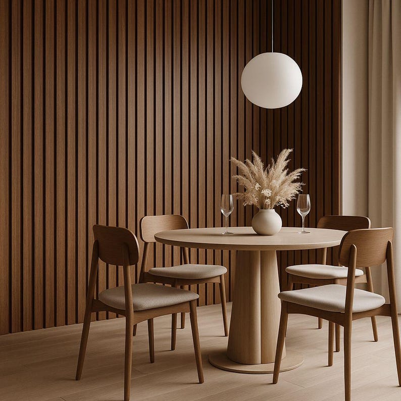 May include: A modern dining room set with a round wooden table, four chairs, and a decorative vase with dried flowers. A large, round pendant light hangs above the table. The walls are paneled with vertical wooden slats.