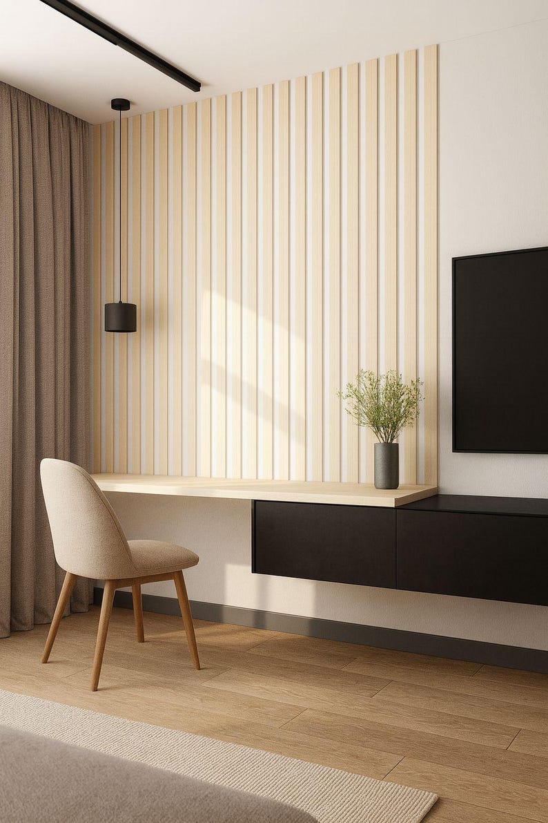 May include: Modern home office setup featuring a light wood desk, a beige chair, and a black storage unit. The wall has vertical wooden panels. A black pendant light hangs above the desk, and a vase with greenery sits on the desk.
