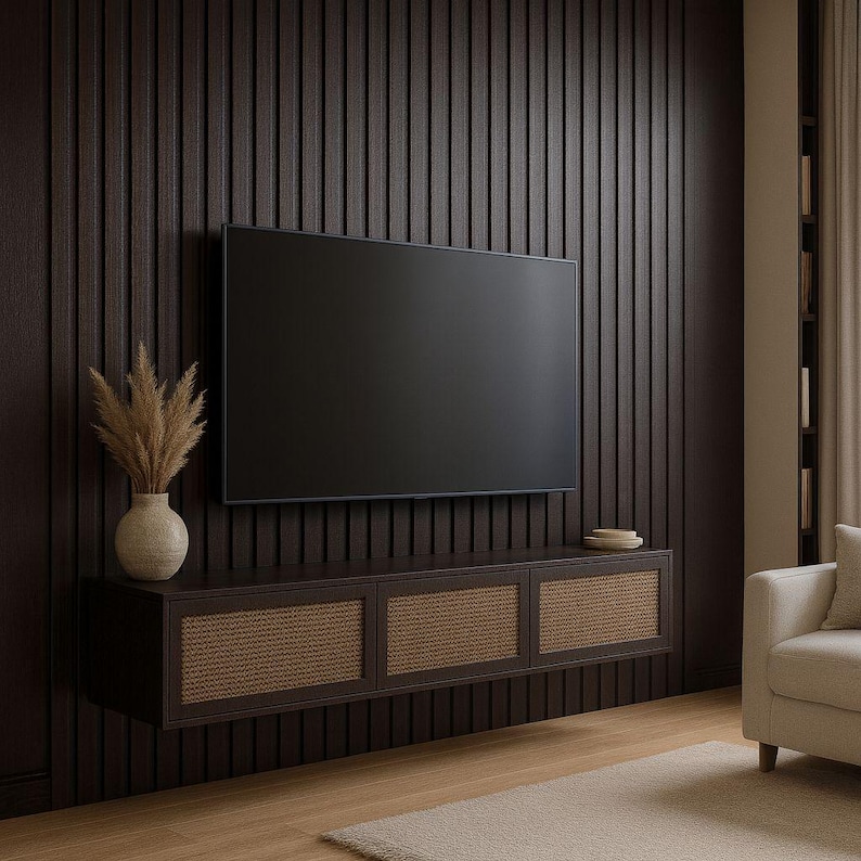Pu&ograve; includere: Un mobile TV sospeso marrone scuro con tre pannelli porta in rattan intrecciato. Un grande televisore nero &egrave; montato sopra il mobile su una parete a doghe verticali marrone scuro. Un vaso beige con piante essiccate &egrave; a sinistra.
