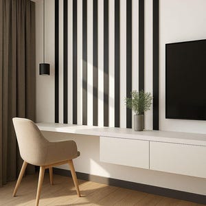 May include: Modern interior design featuring a beige chair, a white desk with drawers, and a black and white striped accent wall. A black pendant light hangs above the desk, and a TV is mounted on the wall.