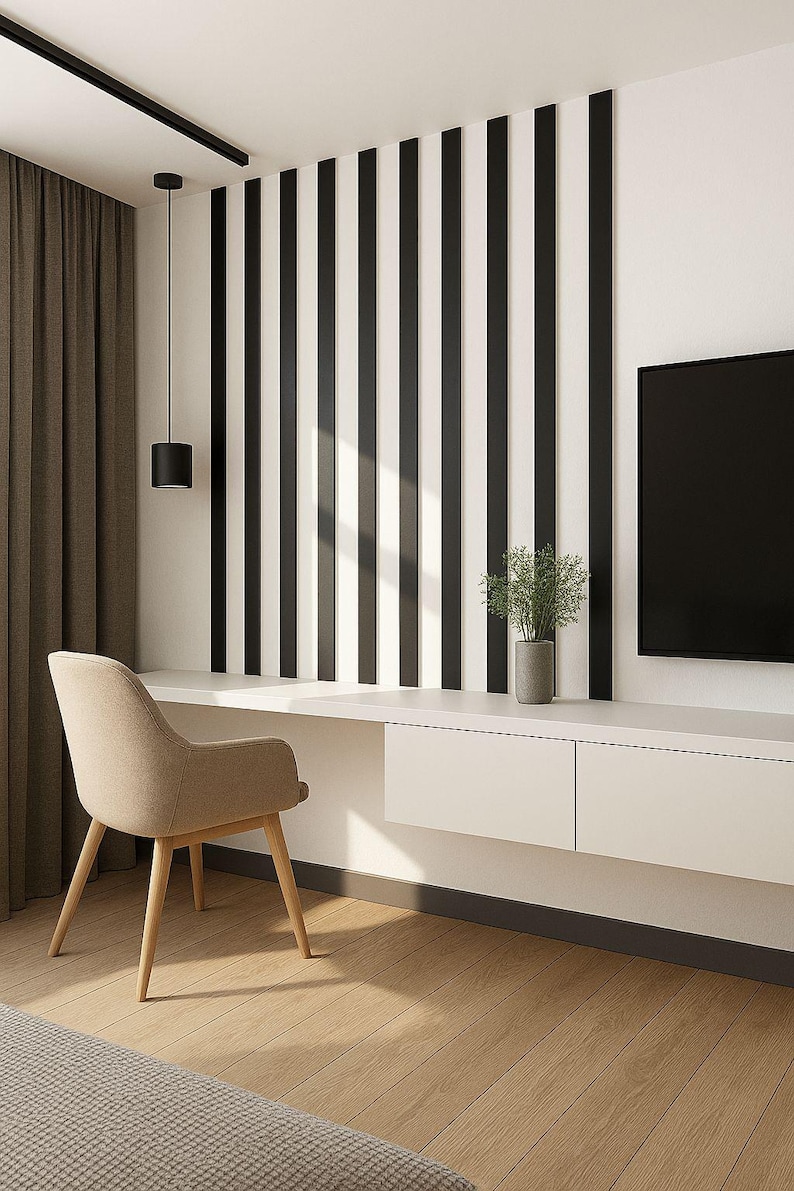 May include: Modern interior design featuring a beige chair, a white desk with drawers, and a black and white striped accent wall. A black pendant light hangs above the desk, and a TV is mounted on the wall.