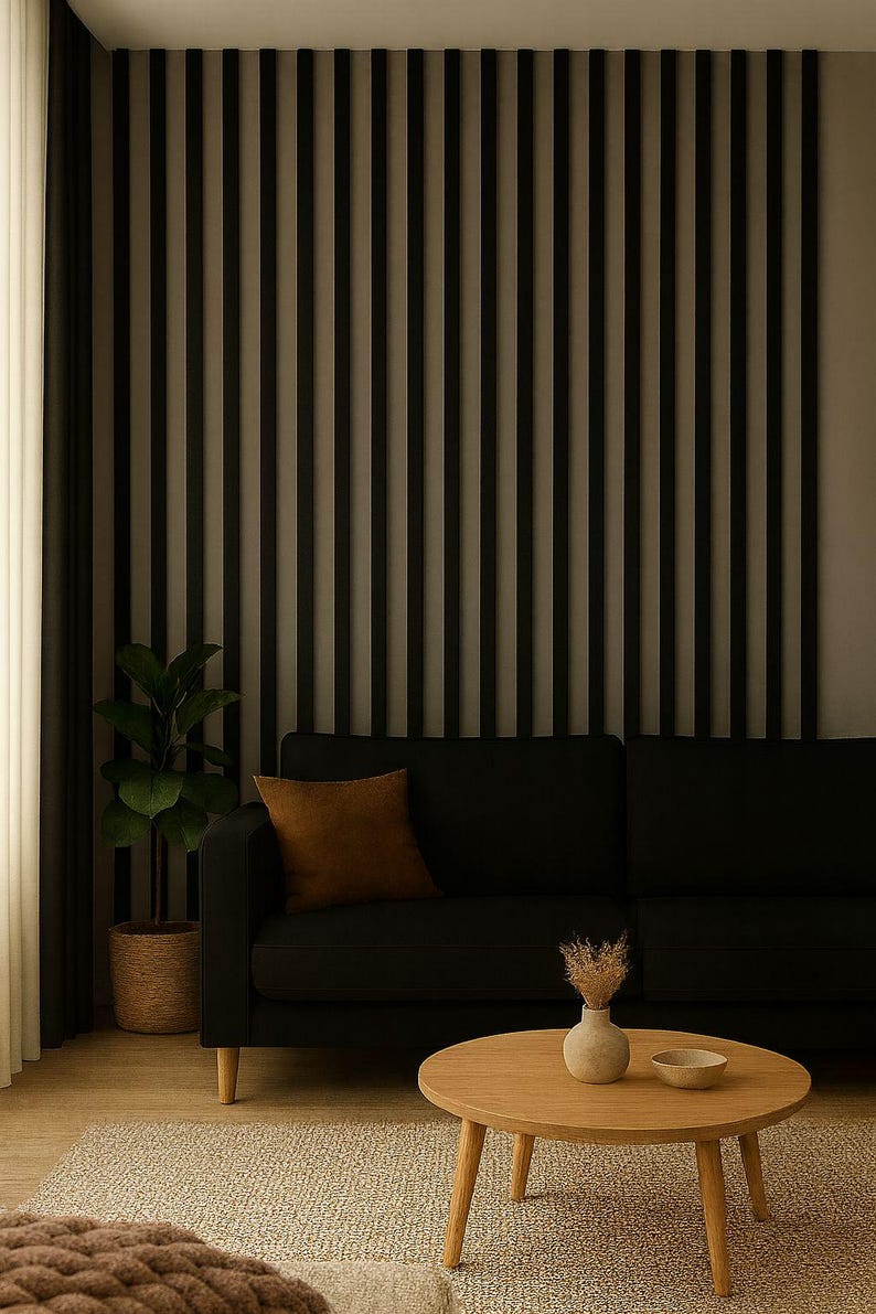 May include: A modern living room with a black sofa, brown throw pillow, and a round wooden coffee table. A decorative wall with vertical black slats is behind the sofa. A potted plant and a beige rug complete the scene.