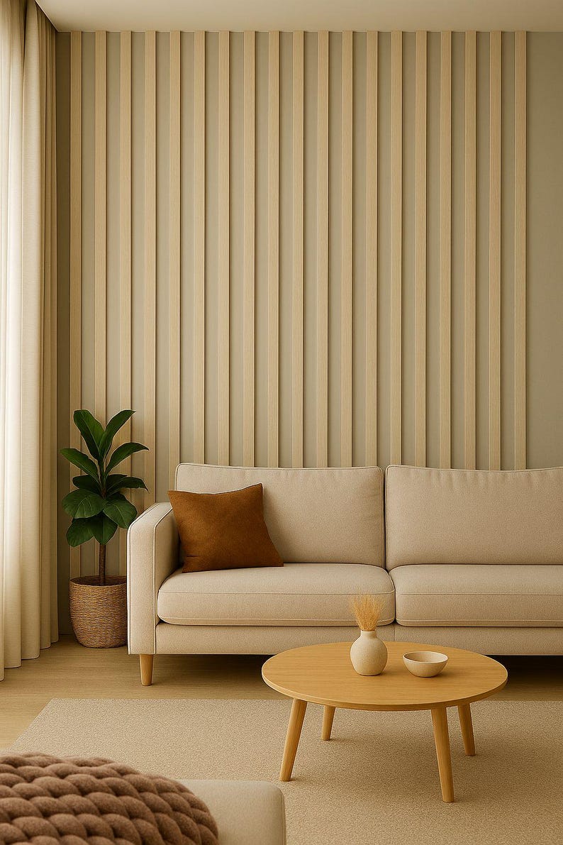 May include: A modern living room scene featuring a beige sofa with a brown throw pillow, a round wooden coffee table, and a potted plant. The wall has vertical wooden paneling, and the room is bathed in natural light.