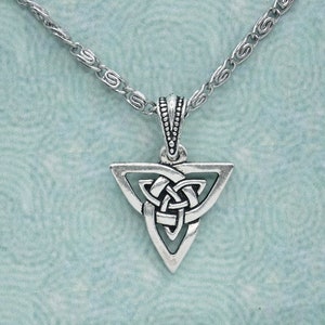 Könnte beinhalten: Eine silberne Halskette mit einem dreieckigen Anhänger in Form eines keltischen Knotens. Der Anhänger ist aus Metall und hat ein detailliertes Knotenmuster.