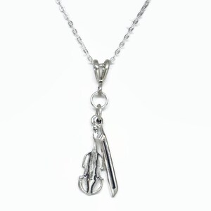 May include: A silver necklace with a charm of a violin and bow.