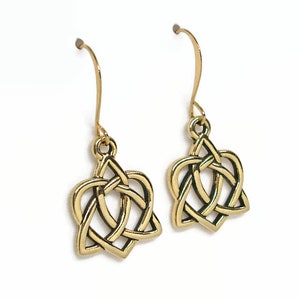 May include: Gold Celtic knot heart shaped earrings. The earrings are made of a gold metal and have a Celtic knot design in the shape of a heart. The earrings are hanging from a gold hook.