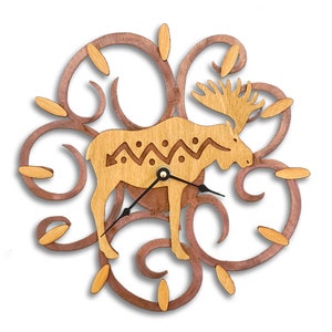May include: A wooden wall clock featuring a stylized moose silhouette with a geometric pattern on its body. The moose is surrounded by a decorative swirl design in a contrasting wood tone.