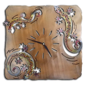 May include: A square wall clock with a wood-like finish features three metal gecko lizards in a colorful design. The clock face is cut out of the wood and has black hands.