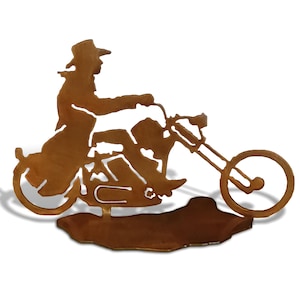 May include: A metal silhouette of a cowboy riding a motorcycle. The silhouette is brown and has a rustic finish.