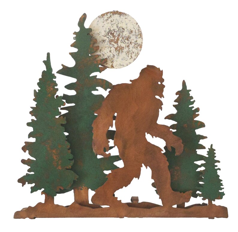 May include: Metal wall art featuring a silhouette of Bigfoot walking through a forest with a full moon in the background. The trees and Bigfoot are rusty brown and green.