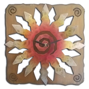 May include: A square wall clock with a sunburst design. The clock face features a spiral center and radiating points in shades of red, yellow, and white. The clock hands are black. The clock is set in a brown square frame with decorative swirls.