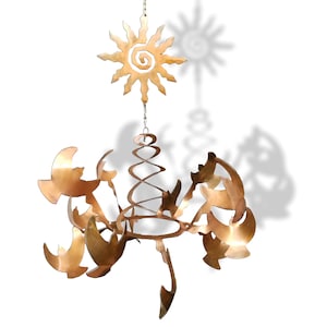May include: A gold metal wind chime with a spiral design and multiple bird shapes. The top of the chime features a sun with a spiral design.