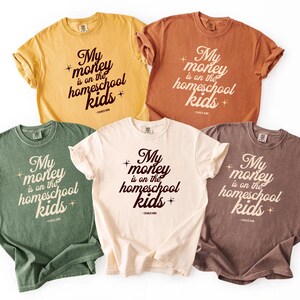 May include: Five different colored t-shirts with the text "My money is on the homeschool kids" in a stylized font. The shirts are in shades of yellow, orange, green, cream, and brown.