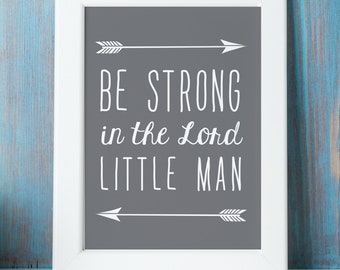 May include: White framed print with a gray background and white text that reads "Be strong in the Lord little man". The text is framed by two white arrows pointing in opposite directions.