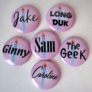 6 pins each with a pink background and single, lit blue birthday candle. Over this is the name of a character in black in a font that matches their personality. Sam, The Geek, Ginny, Caroline, Jake and Long Duck.