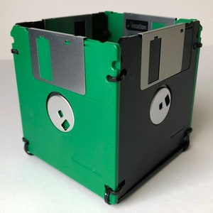 A diskette container shown in green and black with black cable tie fasteners.