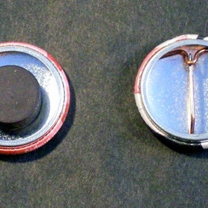 This image shows the backs of two 1 inch round pin-back buttons. The one on the left has a magnet instead of a pin and the one on the right has a pin for wearing on clothes, tote bags, hats, etc.