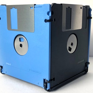 A diskette container shown in light blue and black with black cable tie fasteners.