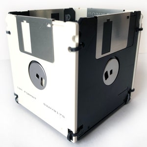 A diskette container shown in white and black with black cable tie fasteners.