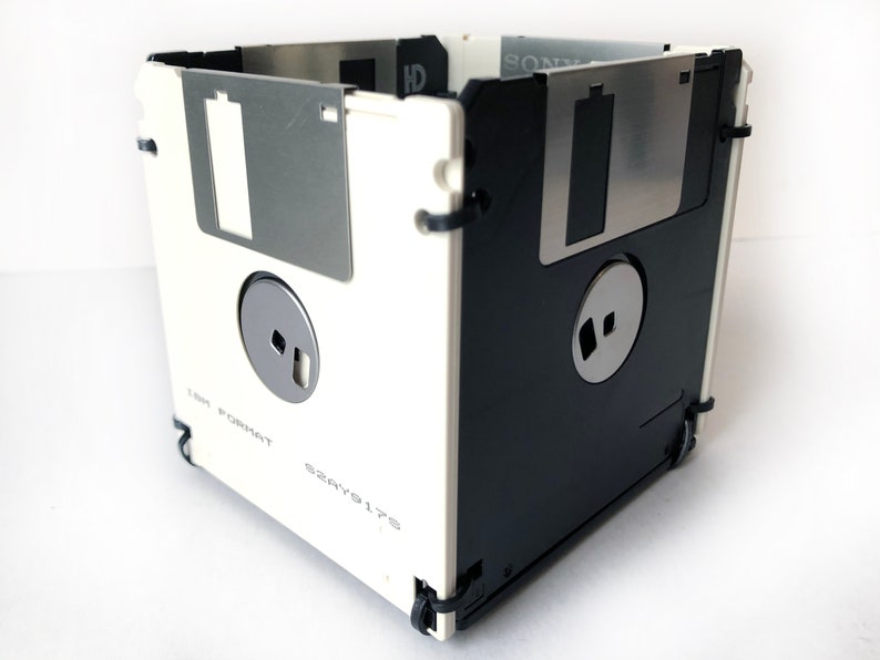 A diskette container shown in white and black with black cable tie fasteners.