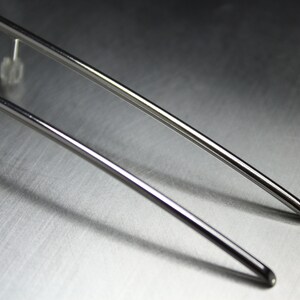May include: Two silver metal earring posts with a curved design.