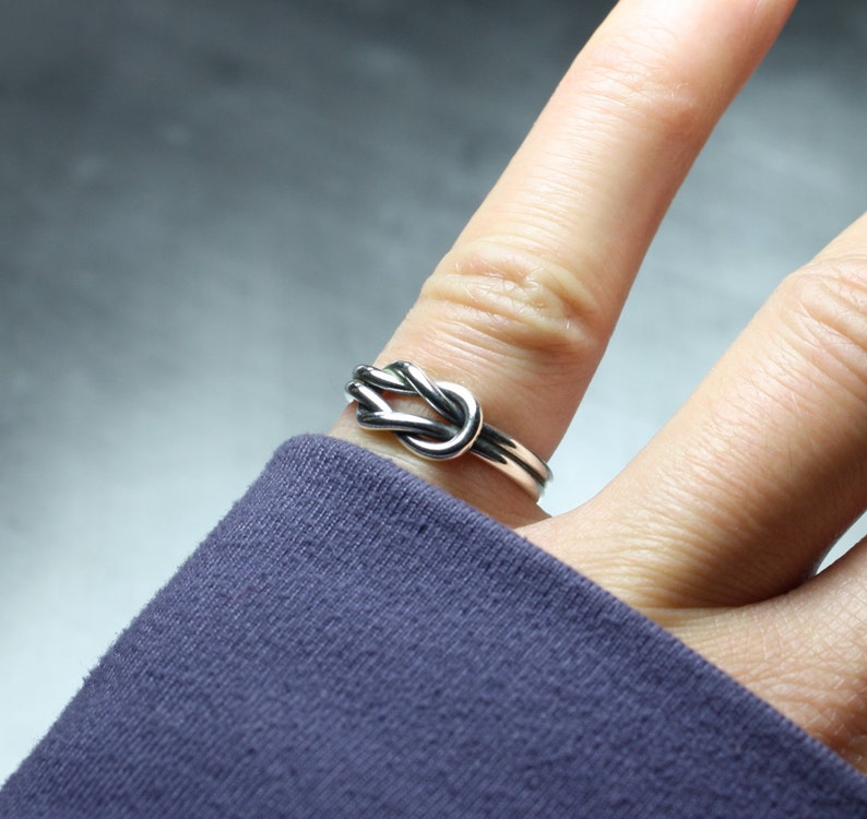 Model showing sterling silver Celtic sailor knot ring on finger.