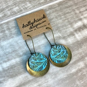 May include: A pair of brass earrings with a blue and green fern pattern. The earrings are handmade in Victoria, BC by hollyhawkdesigns.com.